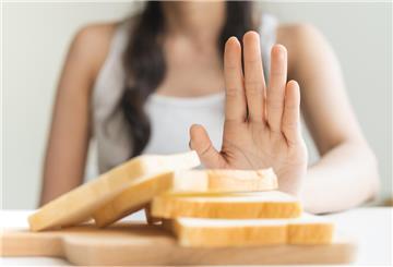 Eine Frau macht eine ablehnende Handbewegung in Richtung eines Stapels mit Toastbrotscheiben.