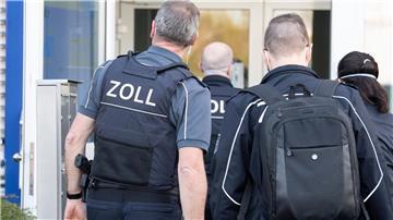 Millionen-Betrug im Baugewerbe: Angeklagte schweigen Zollbeamte betreten bei einer Razzia ein Gebäude.