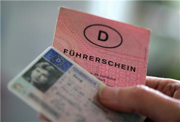 Zwei Führerscheine verschiedener Generationen hält eine Frau in der Hand