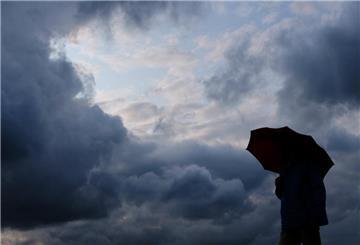 ARCHIV - 12.07.2019, Nordrhein-Westfalen, Duisburg: Ein Mann geht mit einem Regenschirm vor aufziehenden dunklen Wolken spazieren. Nach ersten sonnigen Frühlingstagen schwenkt das Wetter in Nordrhein-Westfalen schon wieder um. Heftiger Starkregen, stürmische Böoen und kleinkörniger Hagel sind möglich. (zu dpa «Prognose: «Unwetter möglich» mit Starkregen, Sturm und Hagel in NRW») Foto: Martin Gerten/dpa +++ dpa-Bildfunk +++