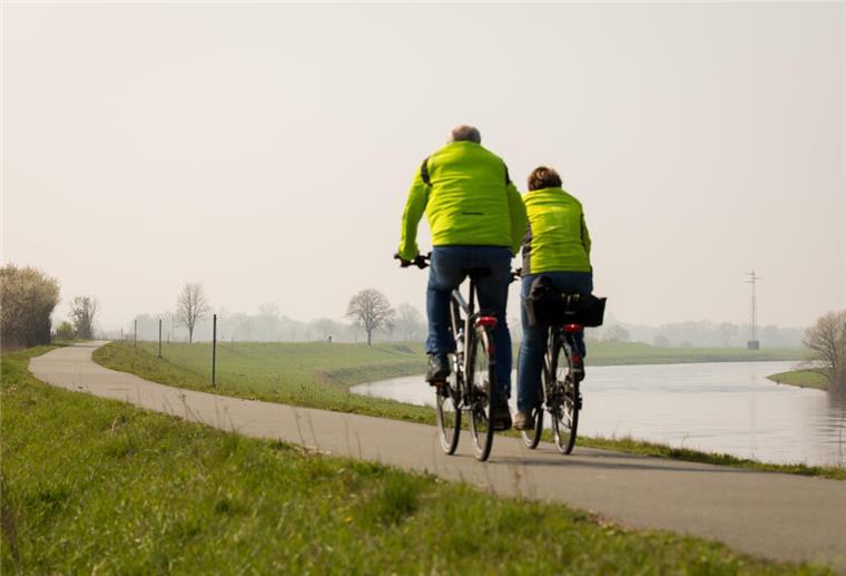 Ein Fahrradfahrer und eine Fahrradfahrerin fahren auf dem Weser-Radweg