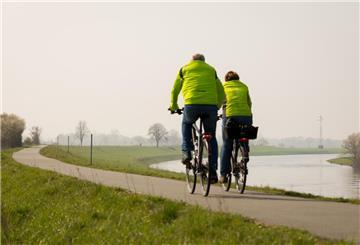 Ein Fahrradfahrer und eine Fahrradfahrerin fahren auf dem Weser-Radweg