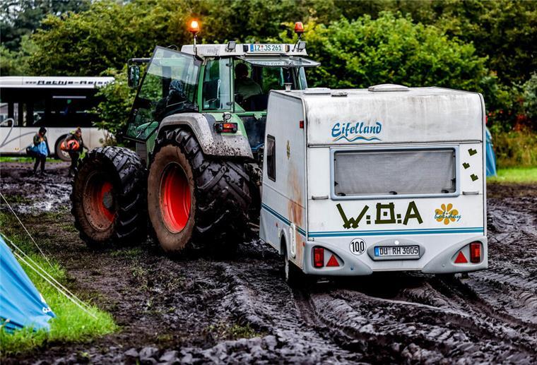 Ein Traktor zieht einen Wohnwagen vom verschlammten Campinggelände des Wacken Open Air