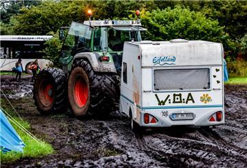 Ein Traktor zieht einen Wohnwagen vom verschlammten Campinggelände des Wacken Open Air