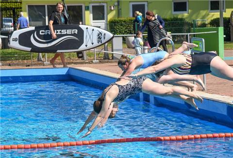 Frauen in Badeanzüge springen kopfüber in ein Schwimmbecken.