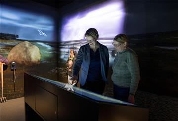 Zwei Frauen stehen in einem Ausstellungsraum und schauen auf eine interaktive Ausstellungstafel