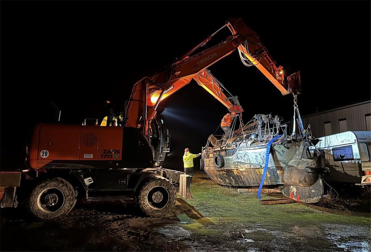 Zwei Bagger heben das im Hafen der Insel Norderney abgestellte und Anfang November gestrandete Segelboot für einen geplanten Abtransport zum Festland an.