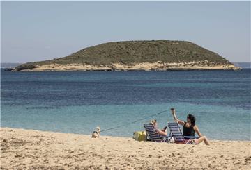 Zwei Frauen mit Hund liegen in Liegestühlen am Strand auf Mallorca.