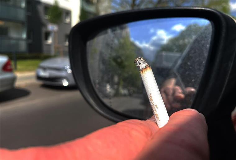 Rauchen im Auto mit Kindern? Diese Strafe könnte bald drohen Eine Person raucht eine Zigarette beim Autofahren.