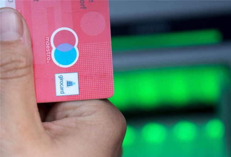 Eine Bankkundin hebt mit ihrer Girokarte Bargeld von einem Geldautomaten ab