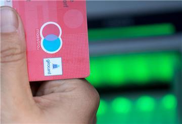 Eine Bankkundin hebt mit ihrer Girokarte Bargeld von einem Geldautomaten ab