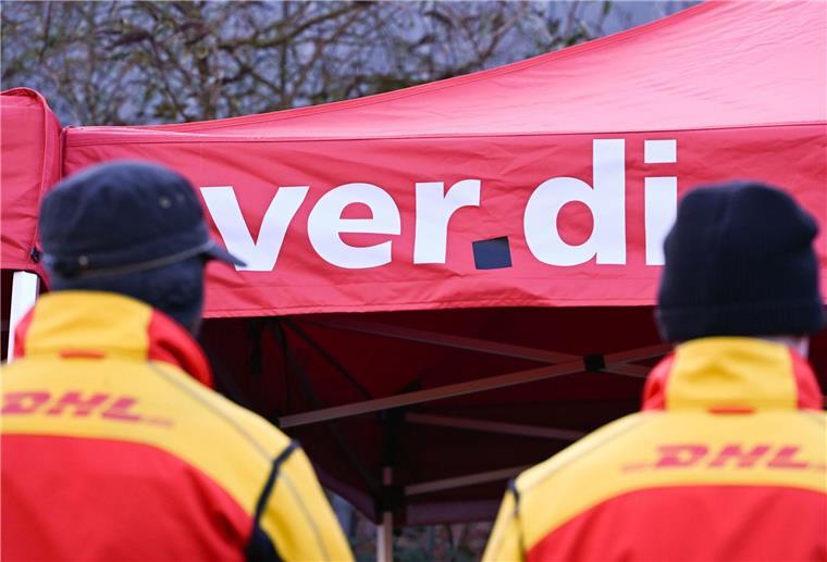 Zwei Mitarbeiter des Logistikkonzerns DHL stehen an einem Warnstreik-Posten der Gewerkschaft Verdi, der sich am Eingang einer DHL-Zustellbasis befindet. Im Tarifkonflikt pocht Verdi auf eine Entgelterhöhung von sieben Prozent höhere Entgelte. (zu dpa: «Verdi bestreikt Briefzentren der Post»)