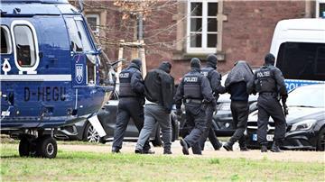 Zwei Personen werden von Polizisten von einem Hubschrauber zu einem Auto geführt.